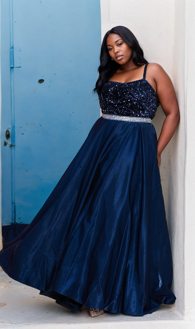 A woman in the Lace-Up Long Plus-Size Prom Dress with Sequins W1018 stands against a light-colored wall near a blue door.